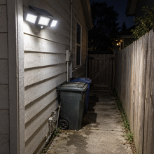 Nightwatch Solar Light lighting a dark side passage and side gate beside a house at night